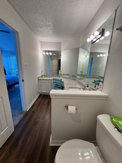 2411 Northlake Ct, Irving, TX 75038 - bathroom with toilet, wood finished floors, a textured ceiling, and connected bathroom