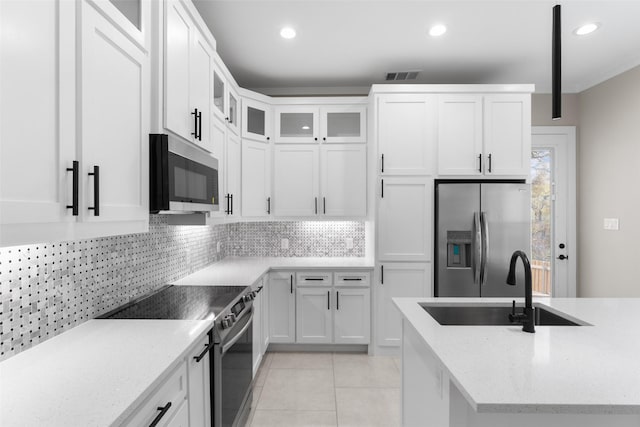 2111 Brookhaven Dr, Dallas, TX 75224 - kitchen with a sink, backsplash, appliances with stainless steel finishes, light tile patterned floors, and white cabinets
