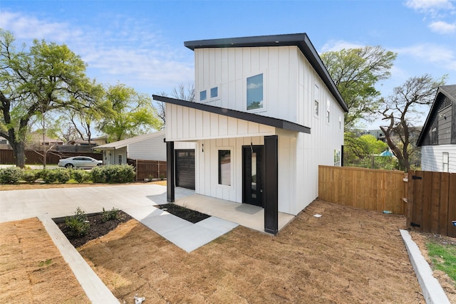 2111 Brookhaven Dr, Dallas, TX 75224 - view of front of house with fence, a patio, board and batten siding, driveway, and a garage