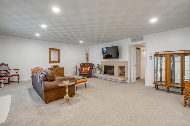 carpeted living room with recessed lighting, a fireplace with raised hearth, baseboards, and visible vents