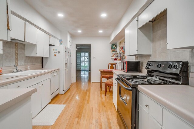 kitchen with white cabinets, light countertops, a sink, and white appliances