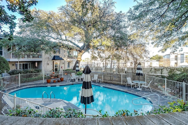 community pool with fence and a patio area