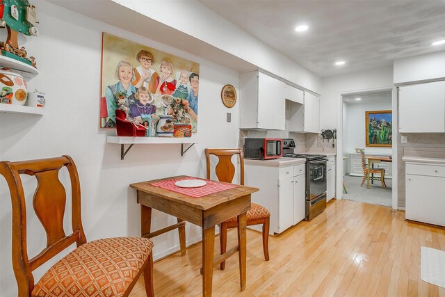 kitchen with white cabinetry, light countertops, black range with gas cooktop, and light wood finished floors