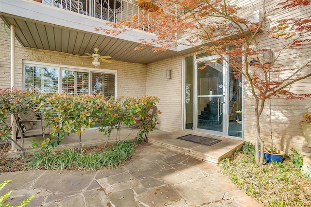 property entrance with a ceiling fan, brick siding, a balcony, and a patio area