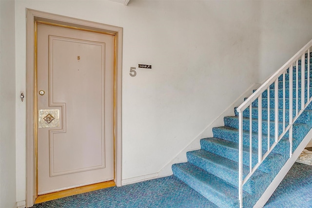 stairway featuring baseboards and carpet