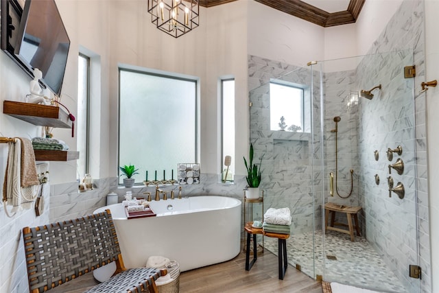 bathroom featuring a stall shower, a freestanding tub, wood finished floors, ornamental molding, and a chandelier