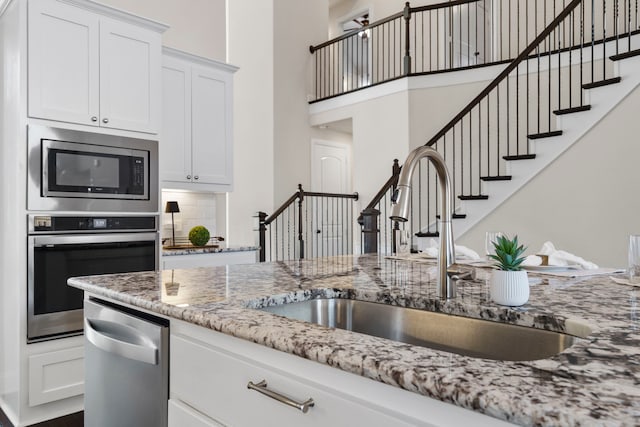 15664 Wild Cherry Ln, Fort Worth, TX 76262 - kitchen with appliances with stainless steel finishes, a sink, light stone countertops, white cabinetry, and a high ceiling