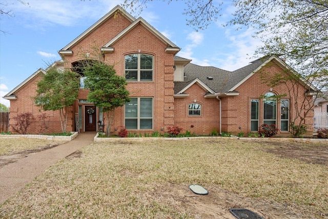 traditional-style house featuring brick siding, a shingled roof, and a front lawn