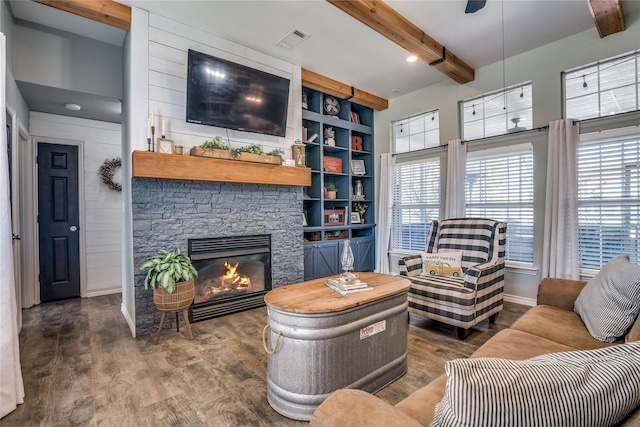 living area with beamed ceiling, visible vents, wood finished floors, and a wealth of natural light