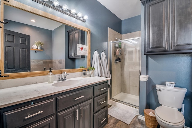 bathroom featuring toilet, vanity, wood finished floors, and a shower stall
