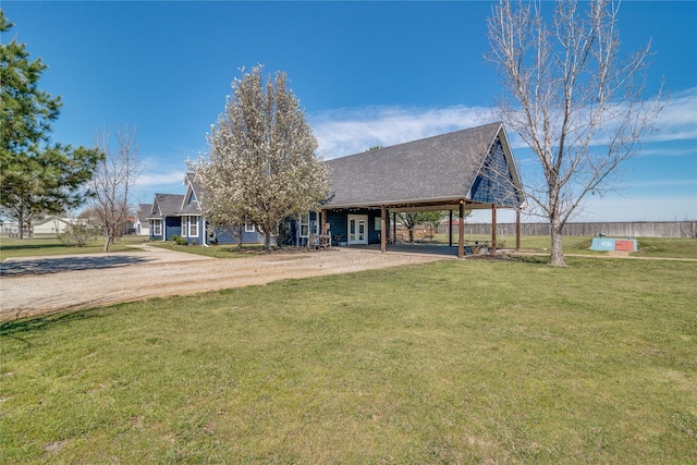 view of front of home featuring driveway, a shingled roof, an attached carport, and a front lawn
