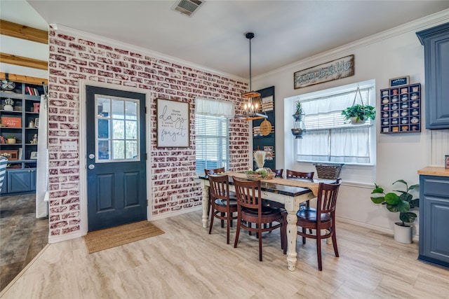 dining space with brick wall, baseboards, visible vents, ornamental molding, and an inviting chandelier