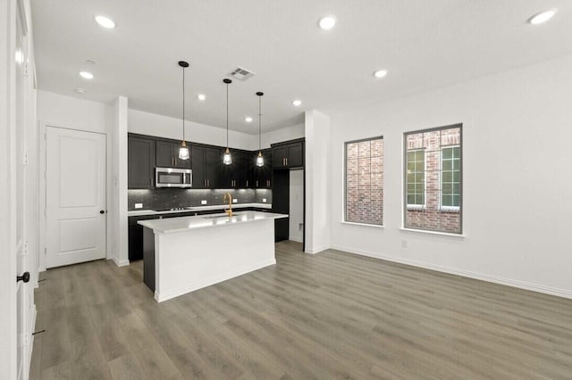 2412 Bulin Dr, Mansfield, TX 76063 - kitchen with stainless steel microwave, wood finished floors, decorative backsplash, light countertops, and recessed lighting