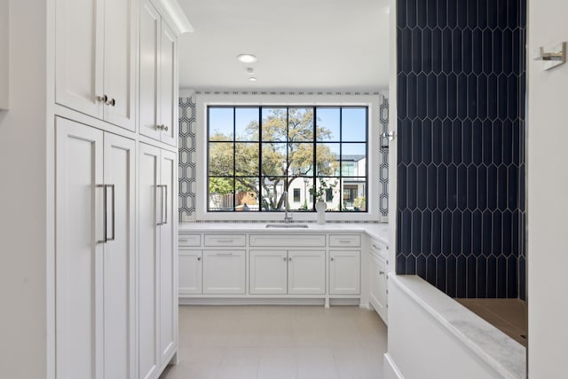 kitchen featuring white cabinets, light stone counters, a sink, and light tile patterned floors