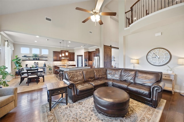 216 Equestrian Rd, Hickory Creek, TX 75065 - living room featuring a ceiling fan, wood-type flooring, a barn door, crown molding, and high vaulted ceiling