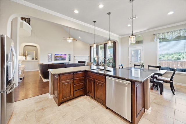 216 Equestrian Rd, Hickory Creek, TX 75065 - kitchen featuring stainless steel appliances, a sink, arched walkways, ceiling fan, and a lit fireplace