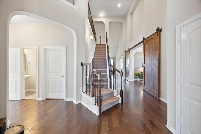 216 Equestrian Rd, Hickory Creek, TX 75065 - entryway featuring arched walkways, hardwood / wood-style flooring, a barn door, stairs, and a towering ceiling