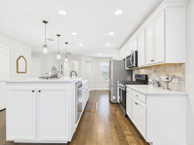 kitchen featuring recessed lighting, white cabinets, appliances with stainless steel finishes, and an island with sink