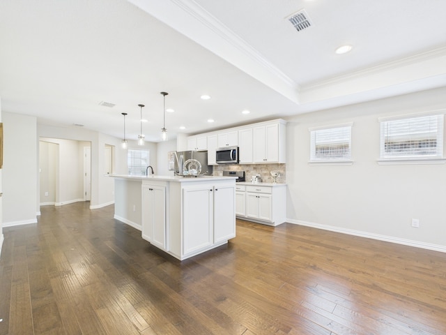 kitchen featuring appliances with stainless steel finishes, visible vents, a healthy amount of sunlight, and a kitchen island with sink