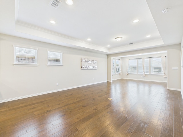 unfurnished living room with ornamental molding, visible vents, a tray ceiling, and wood-type flooring