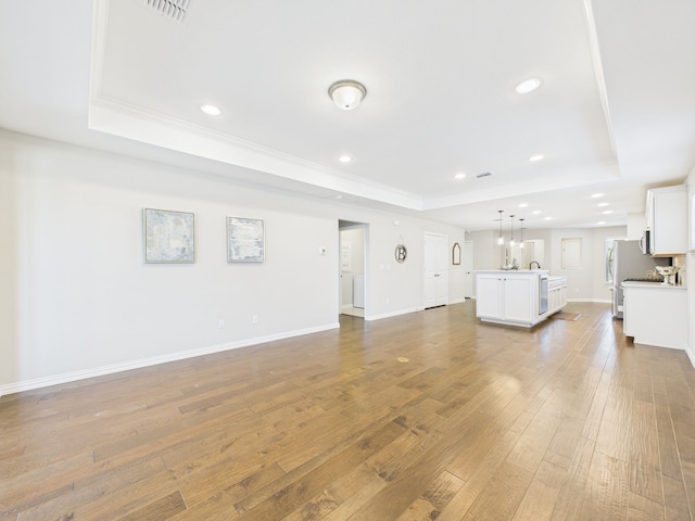 unfurnished living room with ornamental molding, recessed lighting, hardwood / wood-style flooring, and a raised ceiling