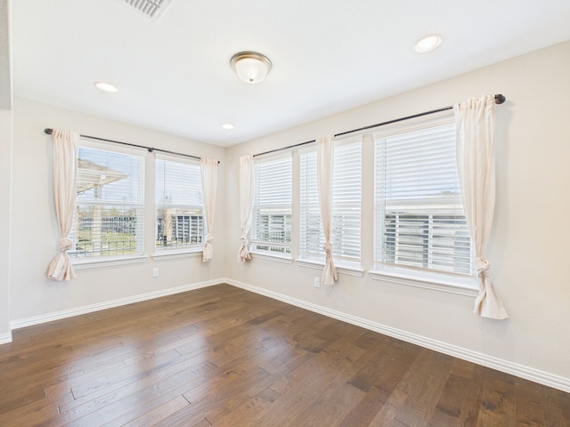empty room featuring visible vents, recessed lighting, dark wood-style floors, and baseboards