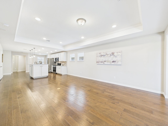7652 Monument Dr, Little Elm, TX 76227 - unfurnished living room featuring a tray ceiling, hardwood / wood-style flooring, crown molding, and recessed lighting