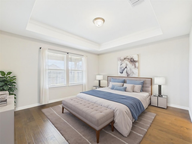 bedroom featuring crown molding, wood-type flooring, visible vents, and a tray ceiling