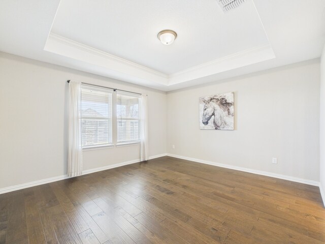 spare room featuring ornamental molding, dark wood-type flooring, visible vents, and a tray ceiling