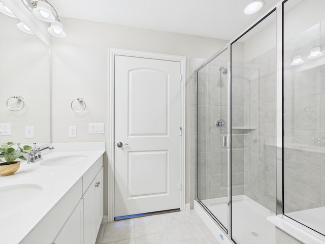 bathroom featuring a stall shower, tile patterned flooring, double vanity, and a sink