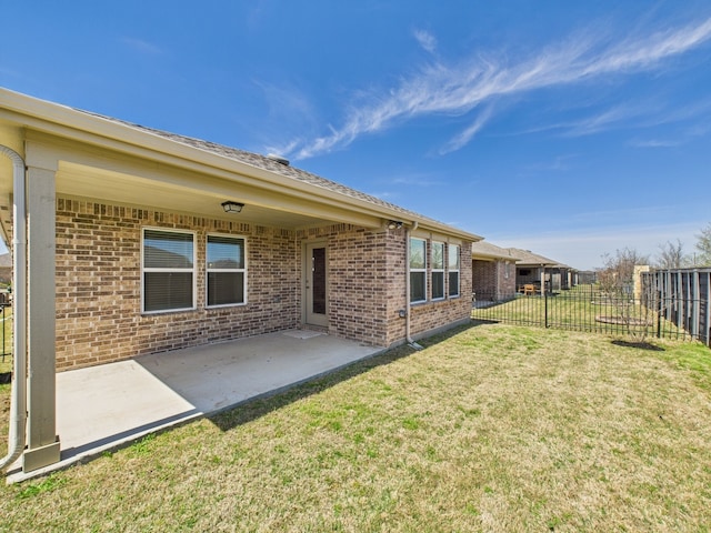rear view of house with a patio, brick siding, fence, and a yard