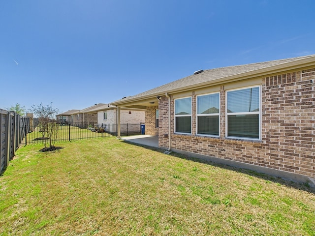 back of house featuring a lawn, a patio, brick siding, and a fenced backyard