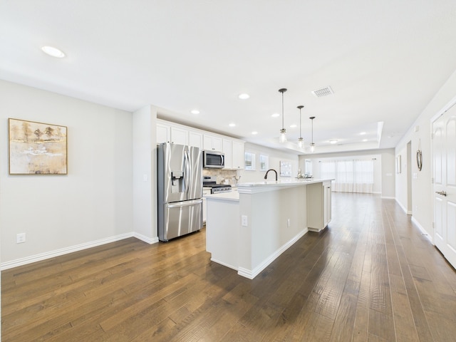 kitchen featuring dark wood-style floors, stainless steel appliances, visible vents, light countertops, and an island with sink