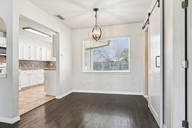10319 Sylvia Dr, Dallas, TX 75228 - unfurnished dining area featuring hardwood / wood-style flooring, a barn door, arched walkways, and a chandelier