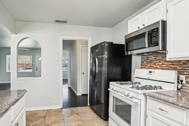 10319 Sylvia Dr, Dallas, TX 75228 - kitchen featuring stainless steel microwave, white gas range oven, decorative backsplash, white cabinetry, and light stone countertops