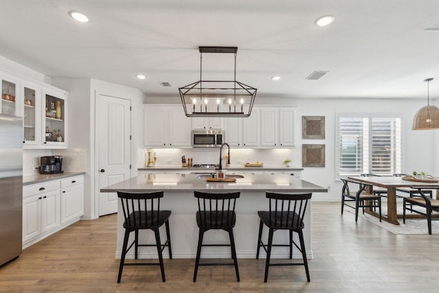 16509 Hidden Cove Dr, Celina, TX 75009 - kitchen featuring stainless steel appliances, a kitchen breakfast bar, tasteful backsplash, white cabinetry, and recessed lighting