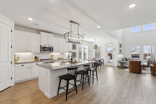 16509 Hidden Cove Dr, Celina, TX 75009 - kitchen featuring appliances with stainless steel finishes, a sink, a breakfast bar area, an island with sink, and light wood-type flooring