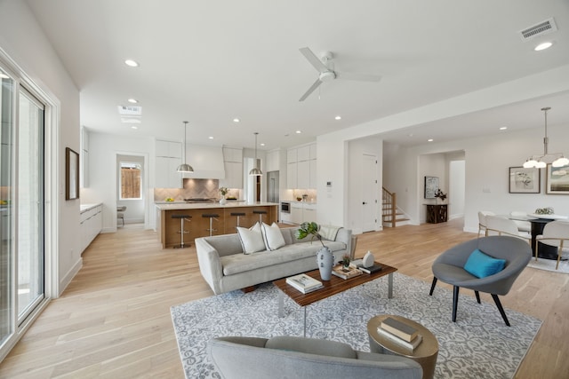 living room with recessed lighting, stairs, visible vents, and light wood-style flooring