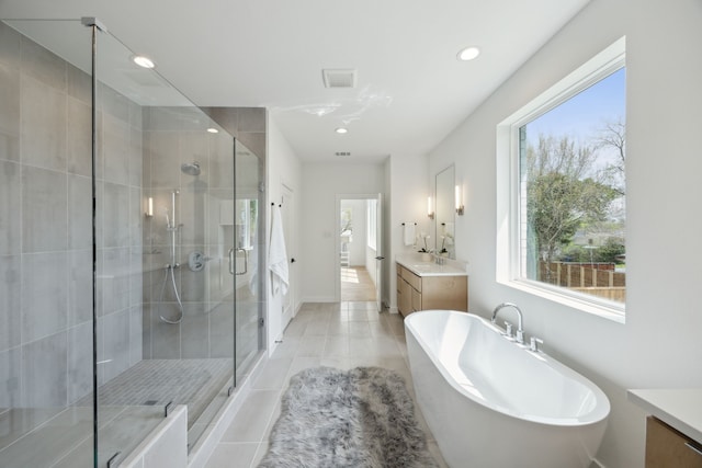 full bath with a stall shower, a freestanding tub, and vanity