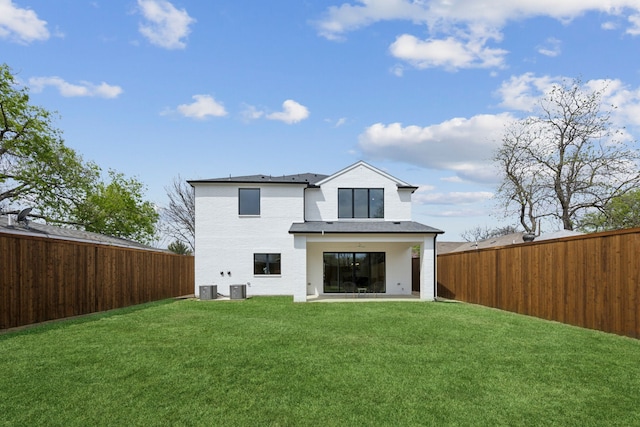 rear view of property featuring a yard, central AC unit, and a fenced backyard