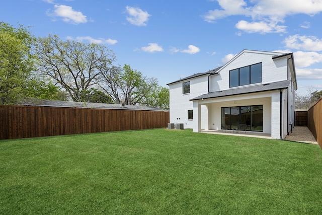 rear view of house featuring a yard, central AC, a fenced backyard, and brick siding