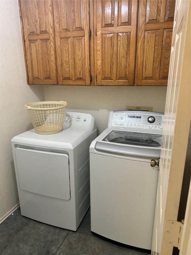 901 Freestone Ct, Arlington, TX 76017 - washroom featuring washing machine and dryer, dark tile patterned flooring, a textured wall, and cabinet space