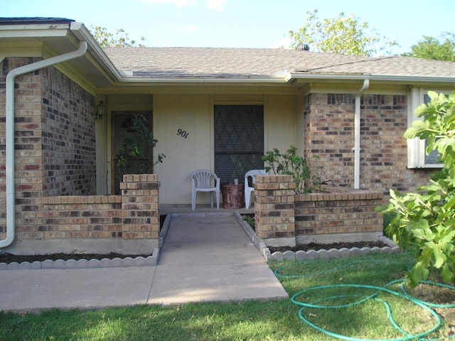 901 Freestone Ct, Arlington, TX 76017 - view of exterior entry with brick siding, a porch, and roof with shingles
