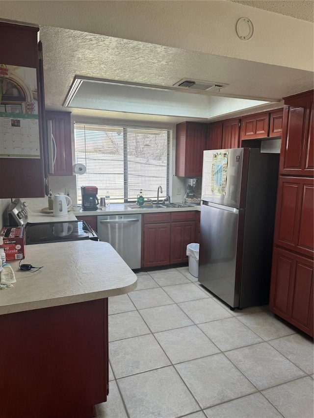 901 Freestone Ct, Arlington, TX 76017 - kitchen with a textured ceiling, visible vents, light countertops, stainless steel appliances, and reddish brown cabinets