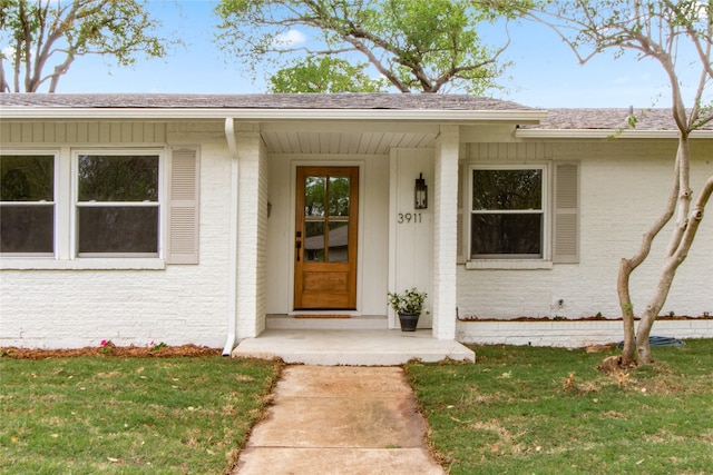 3911 Circle Bluff Ct, Dallas, TX 75244 - view of exterior entry featuring brick siding, a shingled roof, and a yard