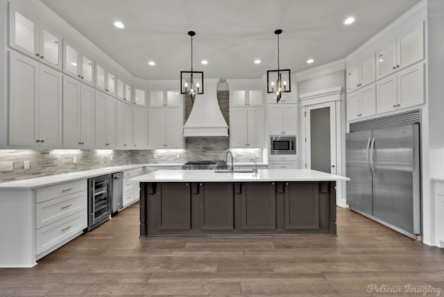 1113 Forest Trail Dr, Shreveport, LA 71106 - kitchen featuring built in appliances, wine cooler, a chandelier, custom exhaust hood, and a kitchen island with sink