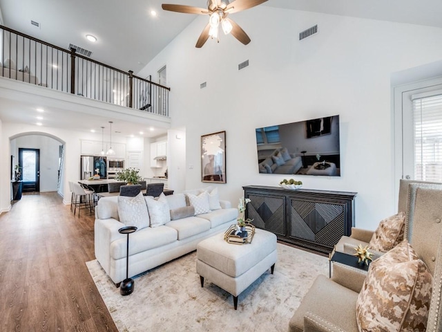 living room featuring arched walkways, ceiling fan, light wood-type flooring, and visible vents
