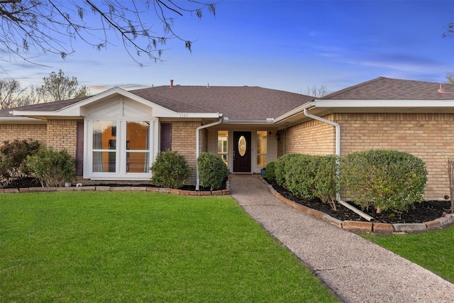ranch-style house featuring brick siding, a front yard, and a shingled roof