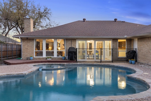 view of swimming pool featuring fence and a pool with connected hot tub