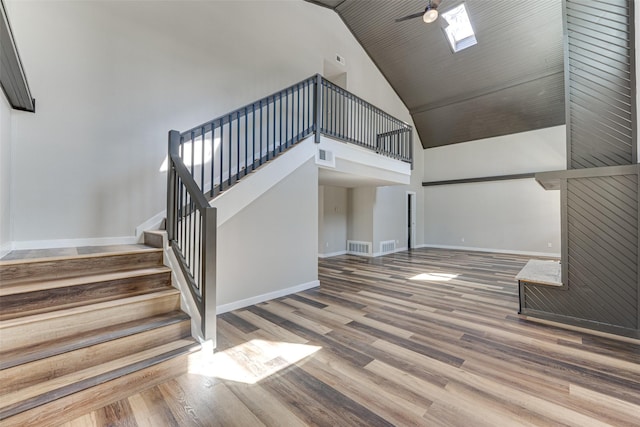 interior space with wood finished floors, high vaulted ceiling, baseboards, and visible vents